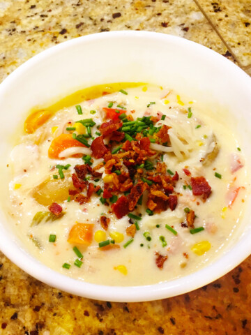 Chicken bacon sweet corn chowder ina white bowl on a counter top.