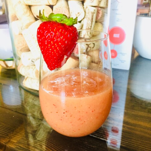 Frozen rosé cocktail in a wine glass garnished with a strawberry