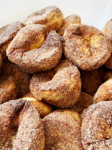 A pile of browned butter cinnamon-sugar popovers on a white background