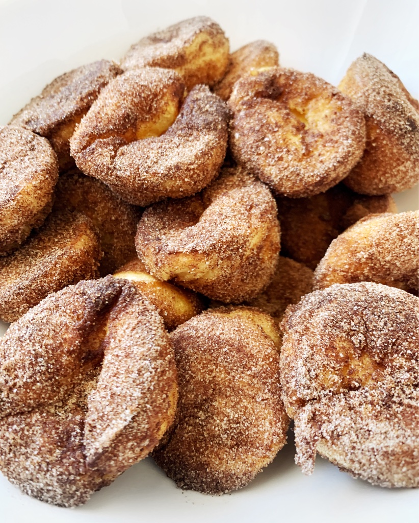 A pile of browned butter cinnamon-sugar popovers on a white background