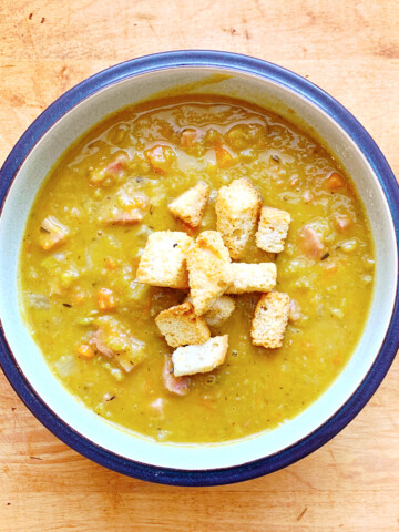 Ham and split pea soup in a bowl on a wood table