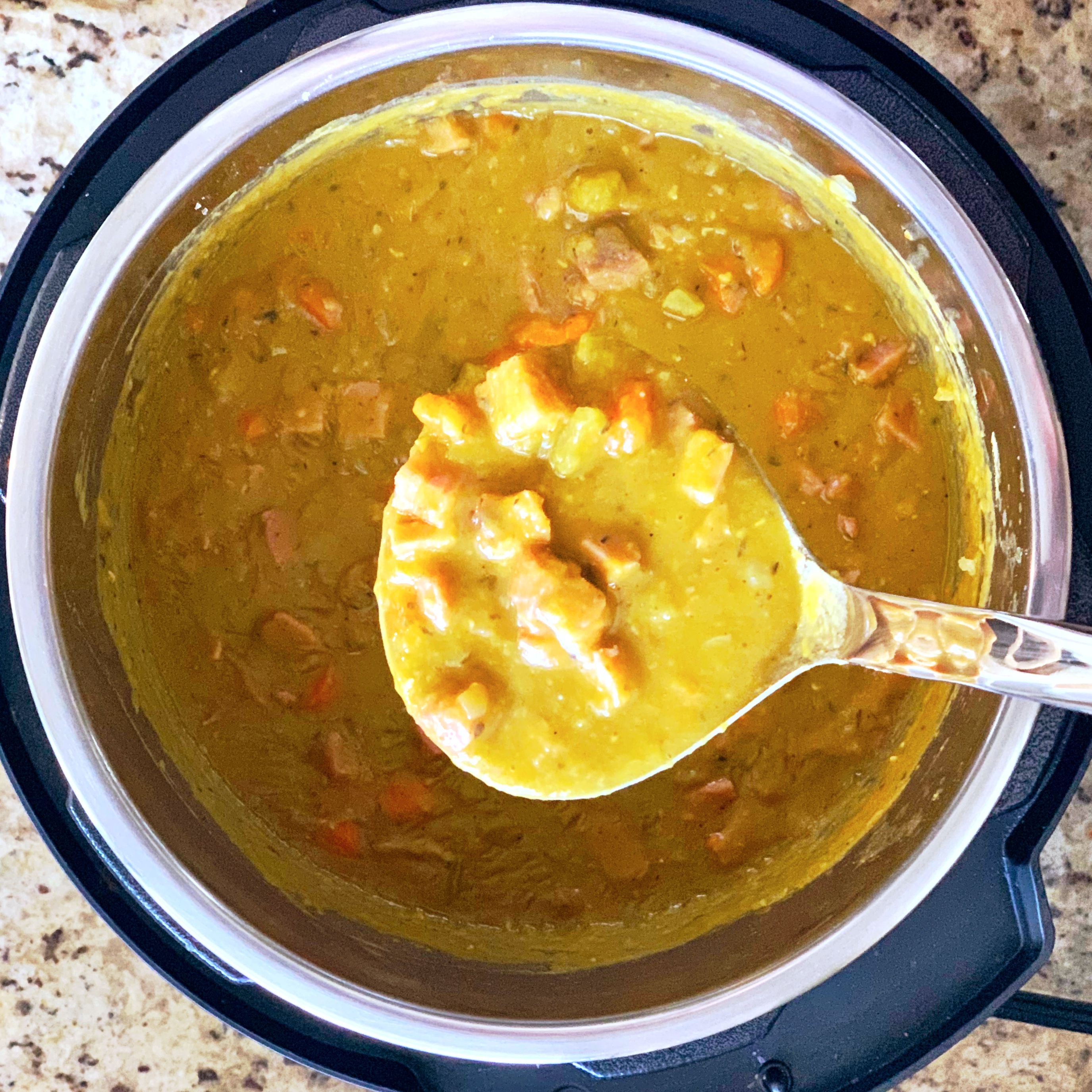 Ham and split pea soup in a ladle above an instant pot.