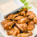 chicken wings on a white platter with celery and yogurt dip