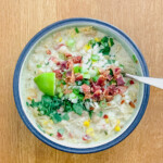 Bowl of white chicken chili with a spoon on a wood table