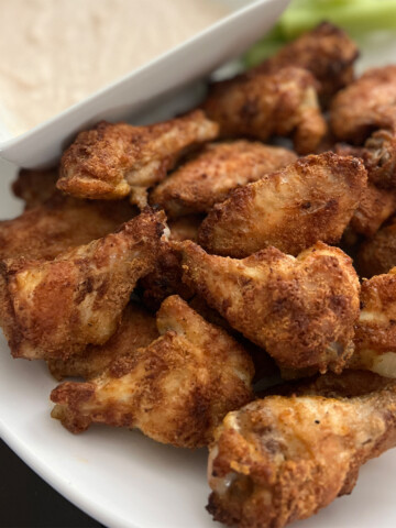 Dry rub chicken wings with dipping sauce on a white plate