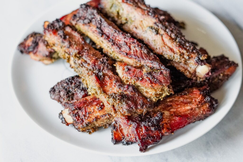 Stacked barbecue ribs on a white plate