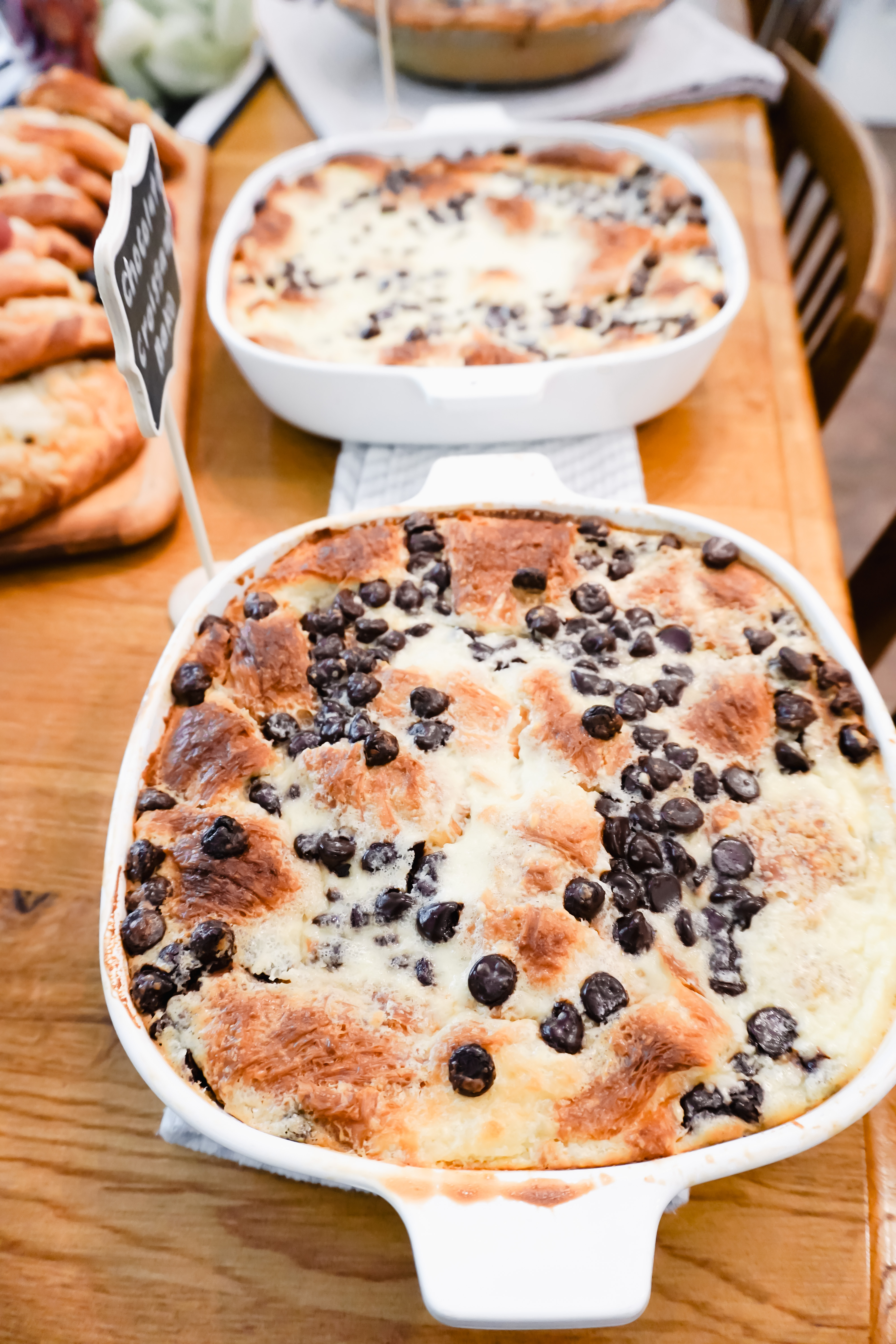 Two chocolate croissant bakes in glass dishes on a wooden table