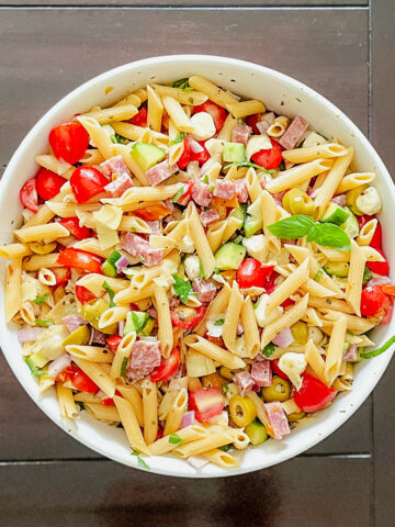 Antipasto pasta salad in a white bowl on a dark table