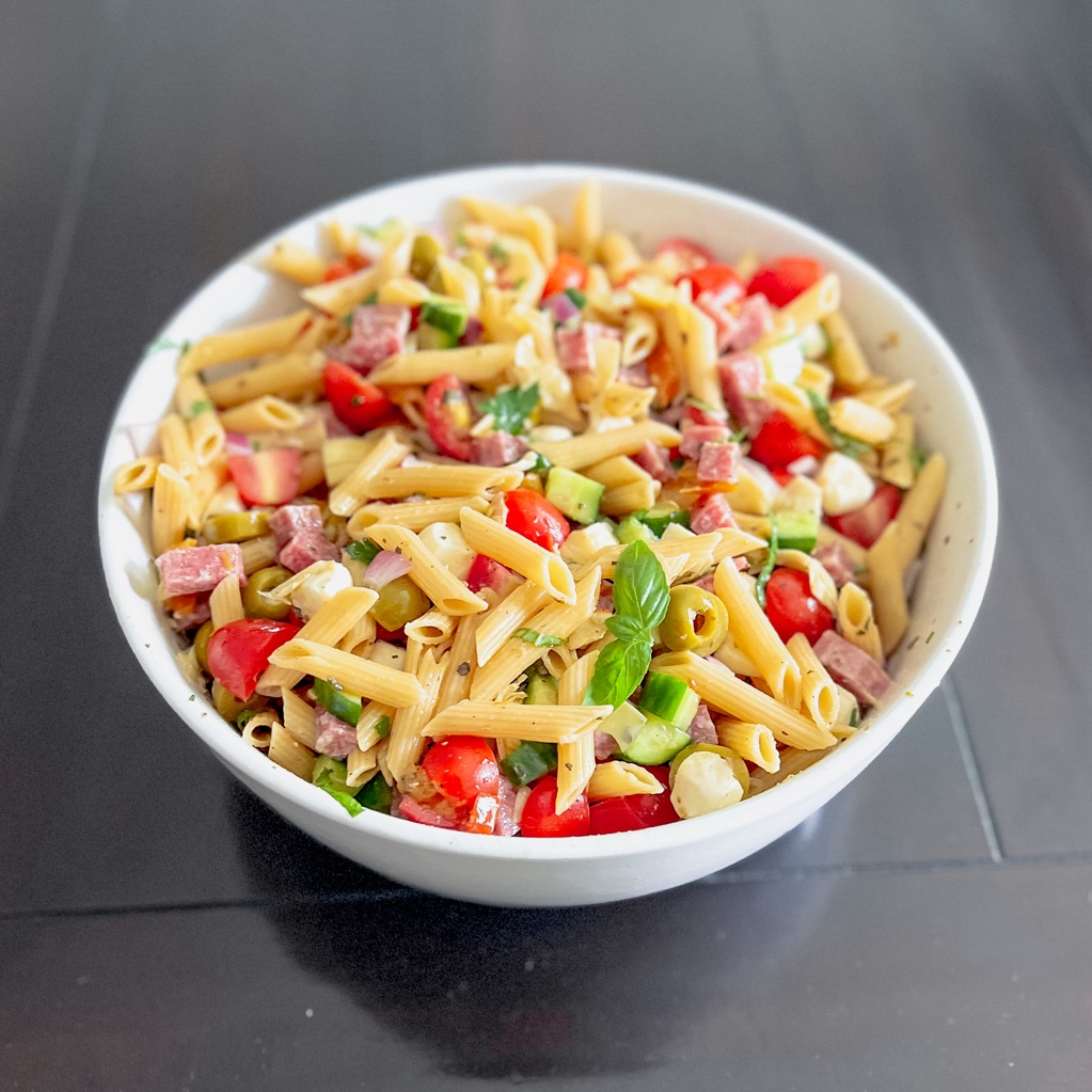 Angled view of antipasto pasta salad in a white bowl on a dark table