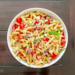 Antipasto pasta salad in a white bowl on a dark table