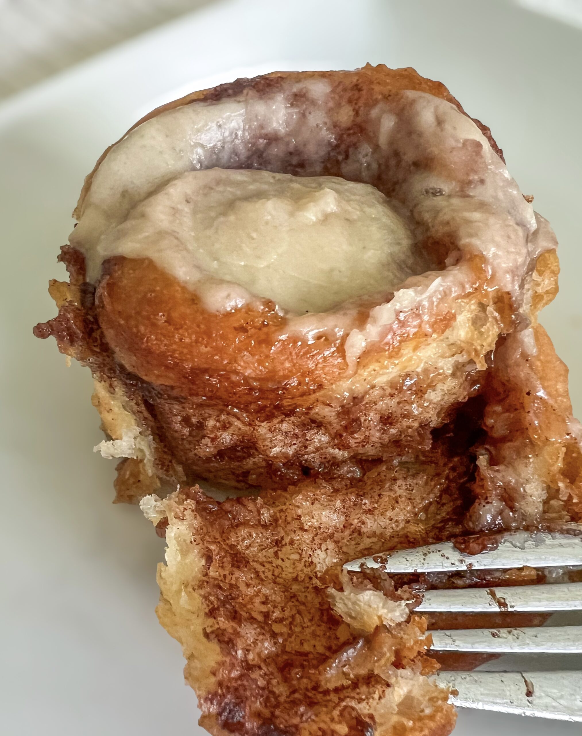 An unraveled cinnamon roll on a white plate 