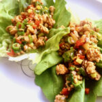 Asian-inspired chicken lettuce wraps on a white plate.