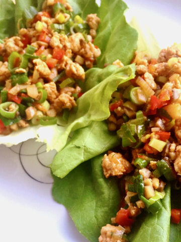 Asian-inspired chicken lettuce wraps on a white plate.