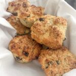 A pile of Irish soda bread muffins in a basket on a white cloth