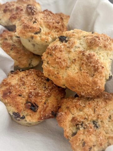 A pile of Irish soda bread muffins in a basket on a white cloth