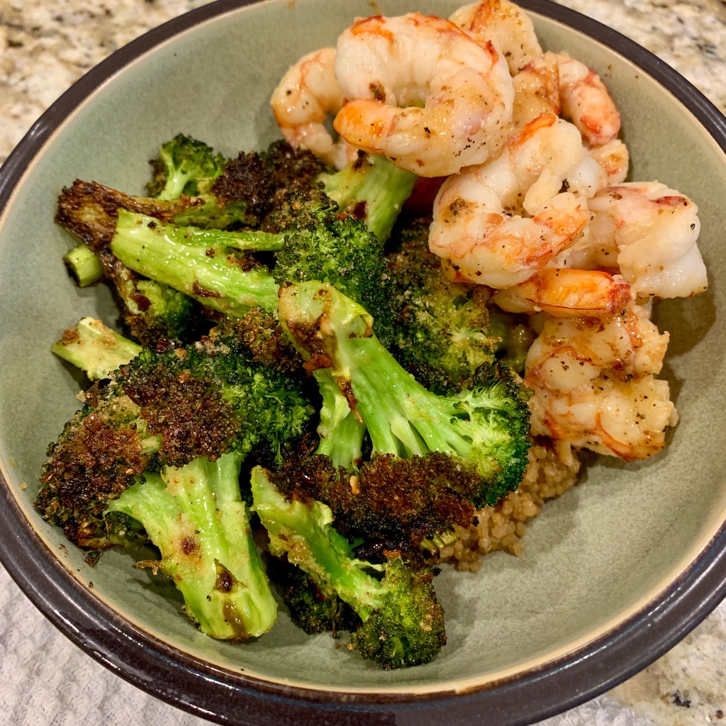 Blasted broccoli over a bed of quinoa with garlic butter shrimp in a bowl.