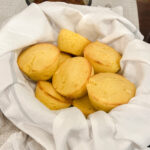 Cornbread muffins with corn in a white flour sack towel-lined basket